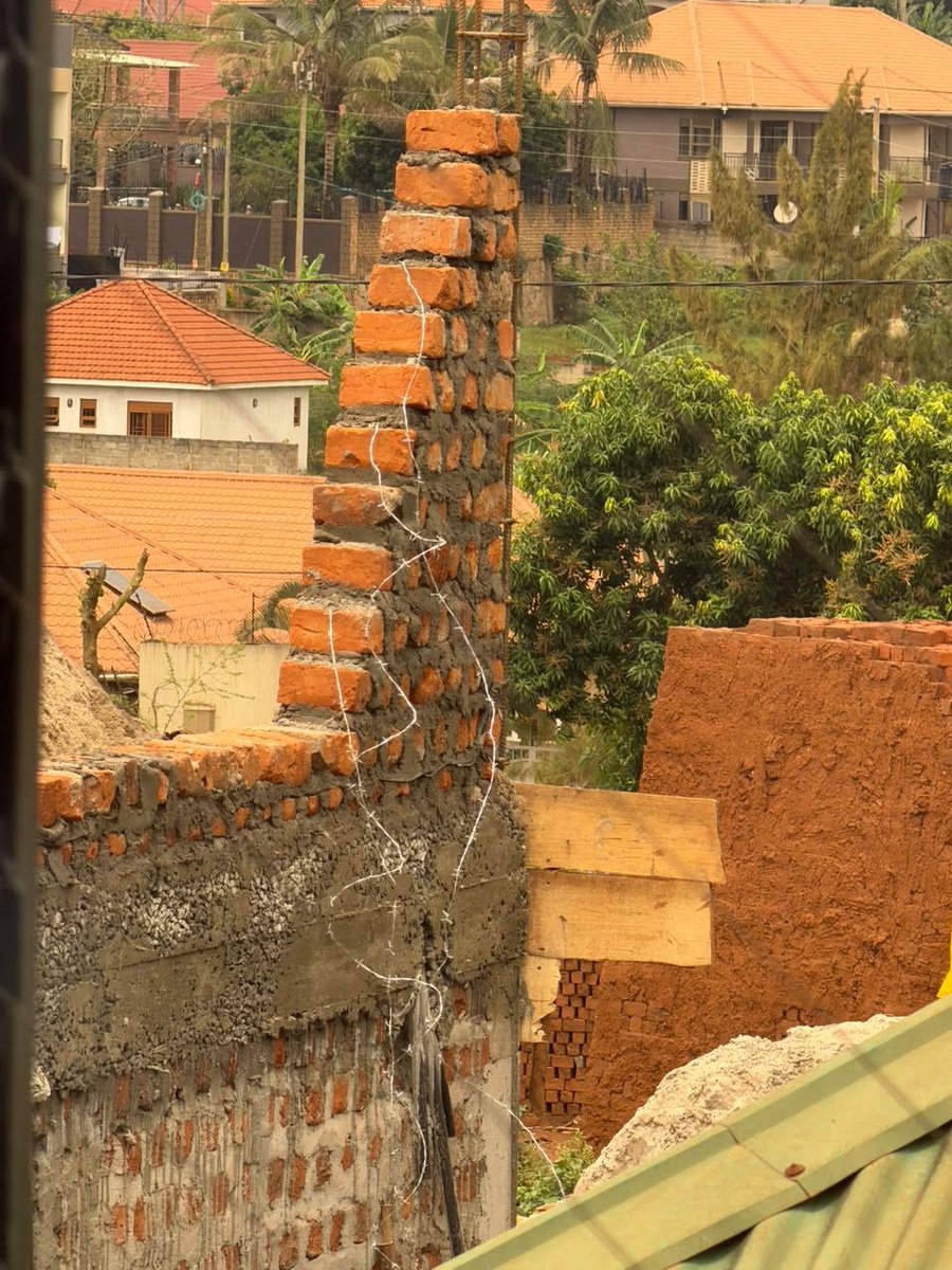 ApolloBuregyeya's tweet photo. The wall is designed. Then somebody remembers payani (hoop iron).
=======

Let us save a homeowner some money today. I mean the person who has paid for a properly designed solid masonry wall, bought the specified materials and then been told that the wall needs hoop iron to become strong. Apparently, the drawing is treated only as a suggestion. The final engineering decision belongs to whoever sends the owner to the hardware shop.

The owner pays because nobody wants to be accused of refusing to buy strength. Unfortunately, buying metal and improving a wall are two different transactions. The hardware shop has answered a question that should first have reached a drawing.

This discussion is not new. Previously, I questioned the growing practice of putting hoop iron in every brick or block wall. The questions were straightforward. Must every wall have it? Does its absence mean that a wall must crack? Is an additional material necessary simply because somebody claims it improves structural integrity? Those questions have not expired because the practice has become popular.

Hoop iron had recognisable jobs before it became a compulsory item on some walling shopping lists. One familiar application was anchoring the wall plate, the timber member connecting the roof structure to the walls. Carpenters also used it to secure timber connections, including half-lap joints. In those applications, one can identify the members being connected and explain what the strap is supposed to hold. Moving the same material into a different arrangement requires a fresh explanation. It does not arrive with transferable powers.

Putting hoop iron into such a wall simply because somebody believes that every wall needs metal is construction superstition. The wall’s strength, stability and resistance to deterioration should already have been resolved in its design. An additional material earns its place by addressing an identified requirement. Being made of steel is not, by itself, a job description.

1. Strength. 

Strength is a material property defined by the amount of material in a unit volume. Materials have a property called density, which describes the amount of material within that volume. The higher the density, the stronger the material. Steel, with its high density, is stronger than concrete. So, you now see the value of that physics lesson on measuring https://t.co/FloeXYh1Fv a wall system, strength is determined by the weakest link, the low-density link. This weakest link is normally the mortar joint. We want the mortar joints to be weak because we want cracks in a wall to pass through the mortar rather than through the bricks. Cement mortar can heal autogenously when conditions allow. It is also easier to repair mortar than a broken brick. Mortar in a wall is therefore required to be weak, with a strength of about 3 MPa.The masonry units, mortar, bonding arrangement and wall dimensions must together provide the required capacity. Loads pass through this assembly to the supporting foundation or beam. The design must address bearing conditions, eccentric loading and the properties of the masonry. So, a piece of metal embedded in the weakest component of a wall, the mortar, does not determine the wall’s strength.

2. Stability. 

Stability is a slenderness ratio issue. A tall Dinka girl is more unstable than a short, stout Muganda girl with big nyash. The Dinka girl will leave you when you run out of cash. The Muganda girl will stay and connect you to a moneylender. I have not experienced either of these scenarios. I’m only quoting what my cousin Paul has just told me. We have just been talking on the phone.Anyway, stability is a section property issue. The wider the wall, the more stable it is. So, a 150 mm thick wall with payani is less stable than a 200 mm thick wall without payani. A 150 mm thick wall with payani is as stable as a 150 mm thick wall without it. In fact, including payani might introduce defects that weaken the wall’s resistance to lateral forces.The wall’s height, thickness and restraints determine how it resists the forces acting on it. A taller wall may require different proportions or additional support. Running a strip horizontally through its mortar does not increase its thickness, shorten its unsupported height or automatically provide lateral restraint. If those are the deficiencies, buying payani leaves the owner with the same problem and a smaller bank balance.

3. Weather resistance. 

Durability, like strength, is defined by the weakest link in an infrastructure system. So, weak blocks and weak mortar will not be fixed by hoop iron. They will disintegrate. Suitable materials, sound workmanship and proper management of water and exposure protect the wall.Adding steel introduces another material that needs protection. Where that protection is inadequate, corrosion can damage the surrounding masonry. The owner may therefore pay to install a future repair bill.
===

The promise of crack control deserves equal scrutiny. A narrow strip cannot be credited with controlling cracks throughout a thick wall merely because steel is strong. Its amount, position, bond and connections must support that claim. Flexible strips laid with inconsistent bedding and casual overlaps do not establish dependable performance. Poor installation can introduce weak interfaces instead.

In my previous discussion, I also challenged the choice of a flat strip by asking why T12 deformed bars, whose ribs are intended to improve grip, were not being considered where reinforcement was actually required. The comparison brings us back to design. The reinforcement type, size, embedment, connections and space available must be considered together. Choosing whatever comes in a convenient roll does not resolve those questions.

This is where faith starts doing work that engineering has not done. The strip disappears into the mortar, the homeowner feels safer, and nobody has demonstrated what changed in the wall’s capacity. Confidence has increased. That is not the same measurement as strength.

Nor does an instruction in a bill of quantities settle the matter. Specifications can contain errors, especially details copied without examining their purpose. Repeat an error often enough and it becomes “normal practice”. The photocopier is innocent. It was never employed to reason.

The other question from my previous discussion remains relevant. Whose standard or design criterion is being followed, and should the supplier decide what the wall needs? A supplier can explain the properties of a product. The designer must establish whether the wall requires it. Selling a material and prescribing its structural application are different responsibilities, even when both people speak confidently.

A solid masonry wall adequately designed without hoop iron needs no ritual addition of payani. If the proposed wall or site conditions change, review the design and specify the necessary response. The homeowner has paid for a functioning wall. They should not also have to finance our construction superstitions.

Lastly, it's funny that even earth walls have now been introduced to payani. At this rate, termites will soon be asked to include it in their anthills before anyone approves their drawings. 😂