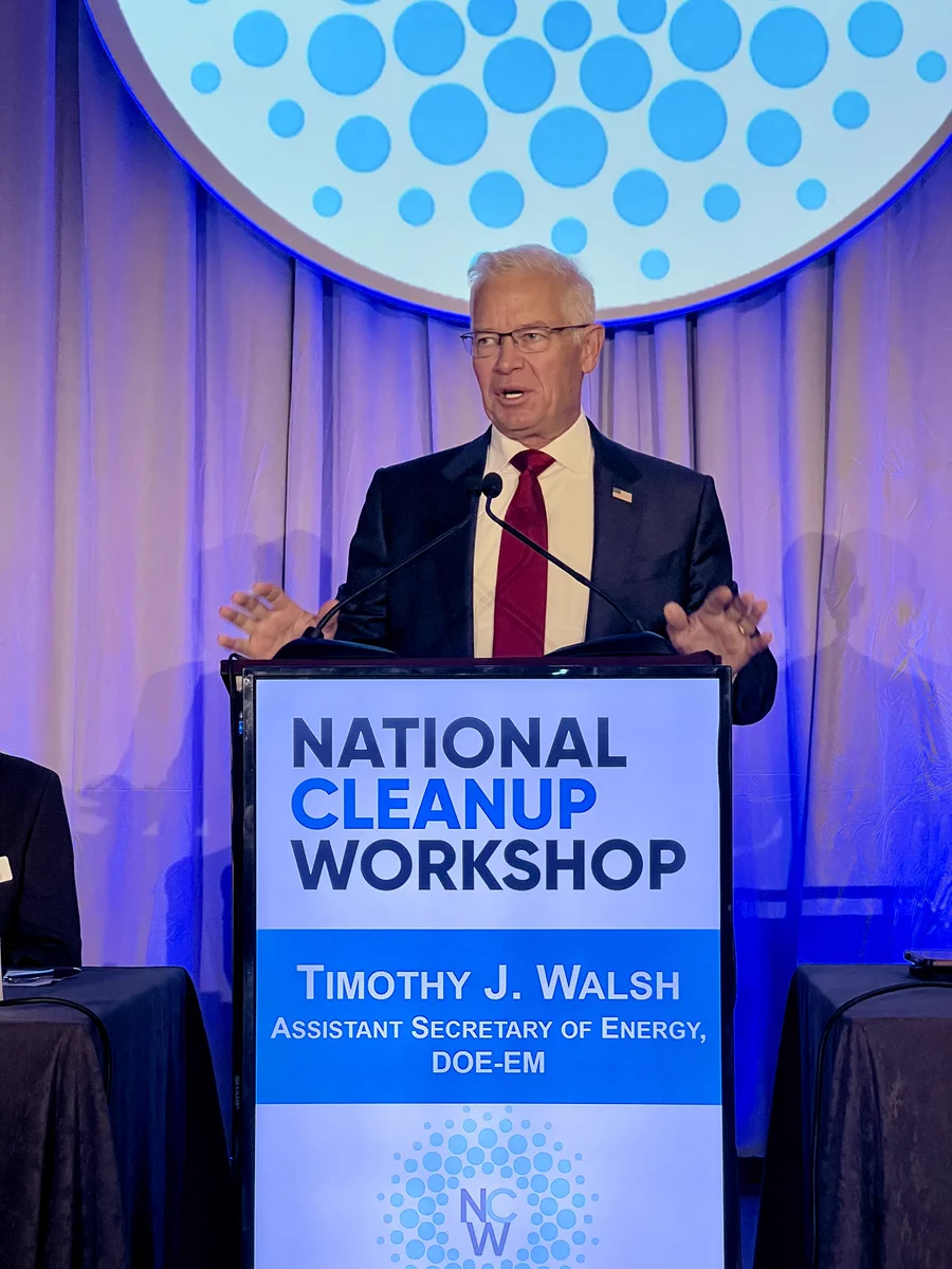 EM Assistant Secretary Tim Walsh delivers keynote address standing behind a podium at the National Cleanup Workshop.