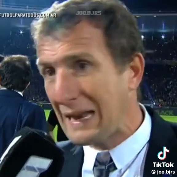 A man in a suit and tie speaking during an interview at a stadium, with watermarks 'FUTBOLPARATODOS.COM.AR' and 'JOO.B.JRS', and a TikTok logo with '@joo.bjrs'.