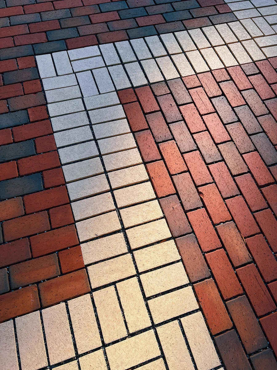 Close-up of a brick pavement with alternating red and white bricks forming a geometric pattern.