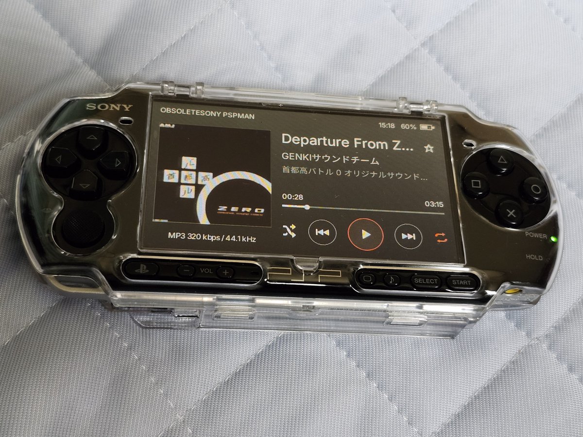 Black Sony PSP displaying PSPMAN's album artwork and playback controls