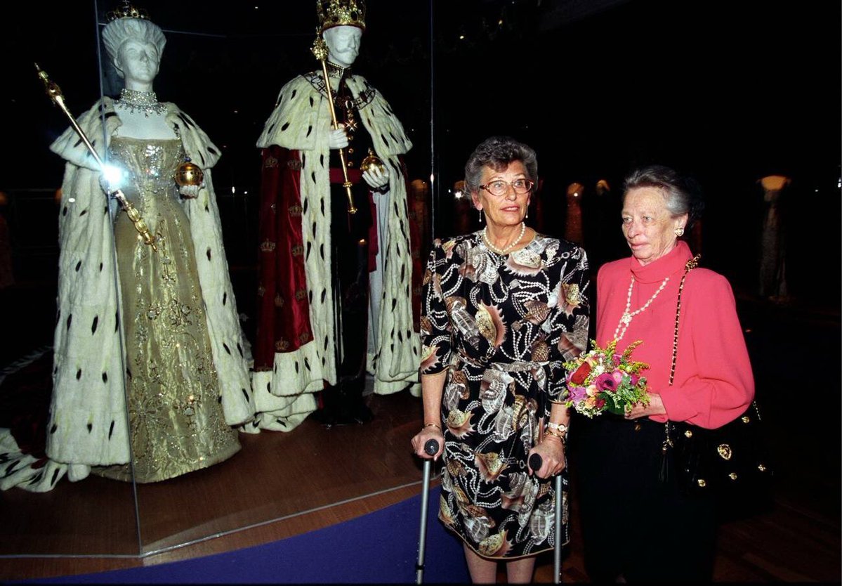 implmaterial's tweet photo. Princess Astrid &amp; Princess Ragnhild in front of King Haakon VII &amp; Queen Maud’s 1905 Coronation Robes at the ‘Queen Maud — Royal Fashion’ Exhibition, 1995 https://t.co/Q3MVMUo1cd