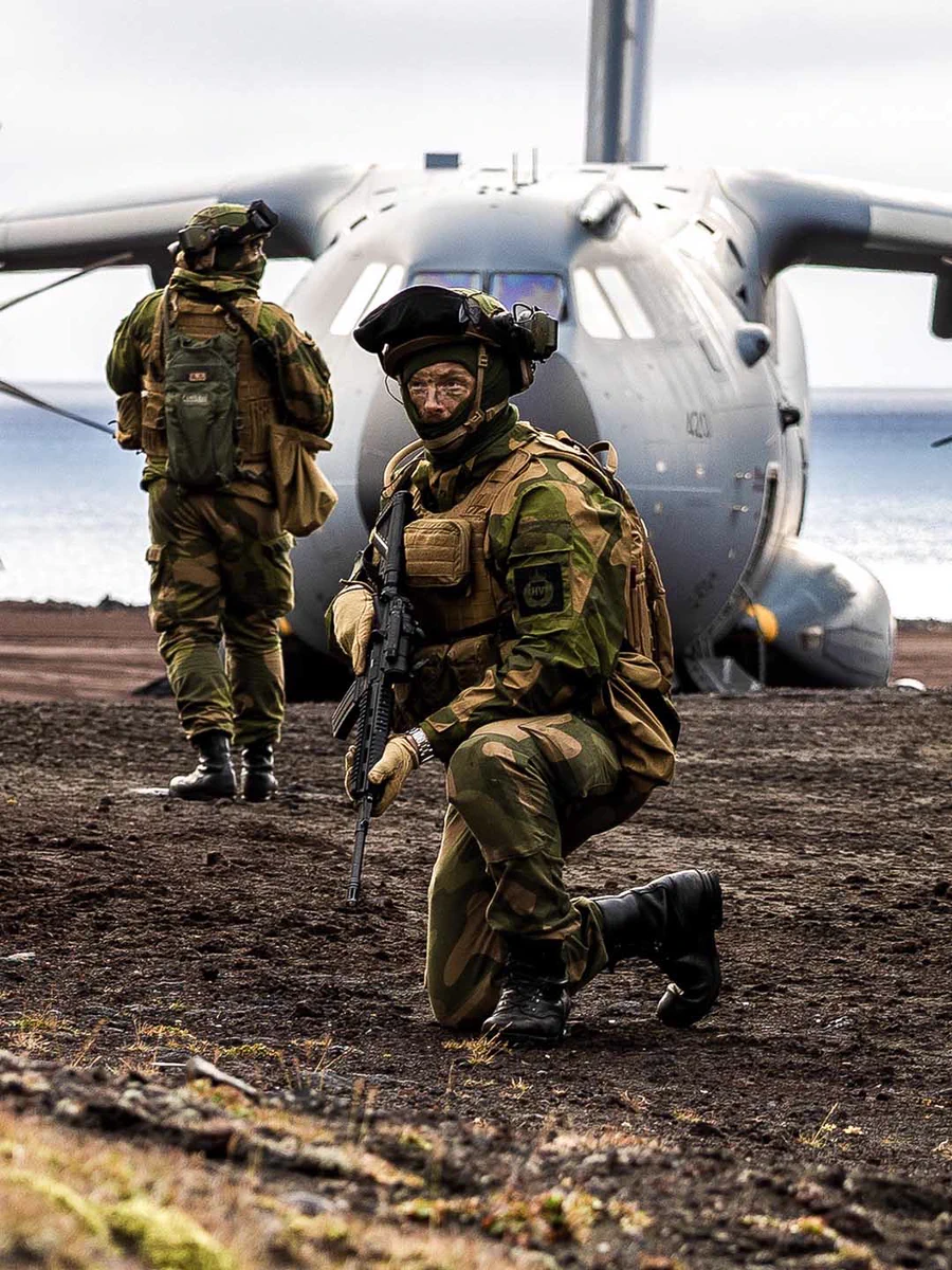 Soldiers in combat gear beside a military aircraft on rough terrain. Photo by UK MOD © Crown copyright 2026.