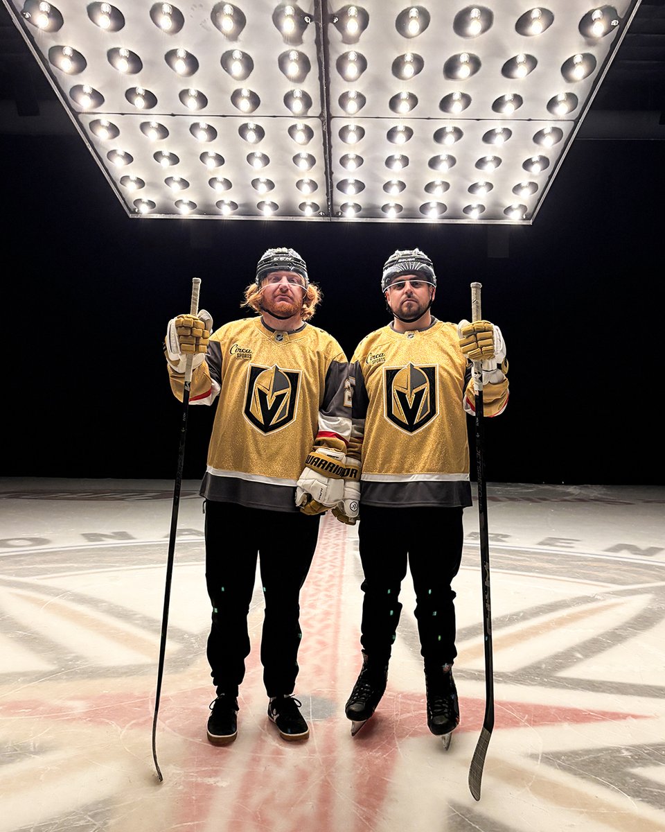 Liam Blutman & Jeff D. Lowe stand on the ice at City National Arena in Golden Knights gear under a panel of lights