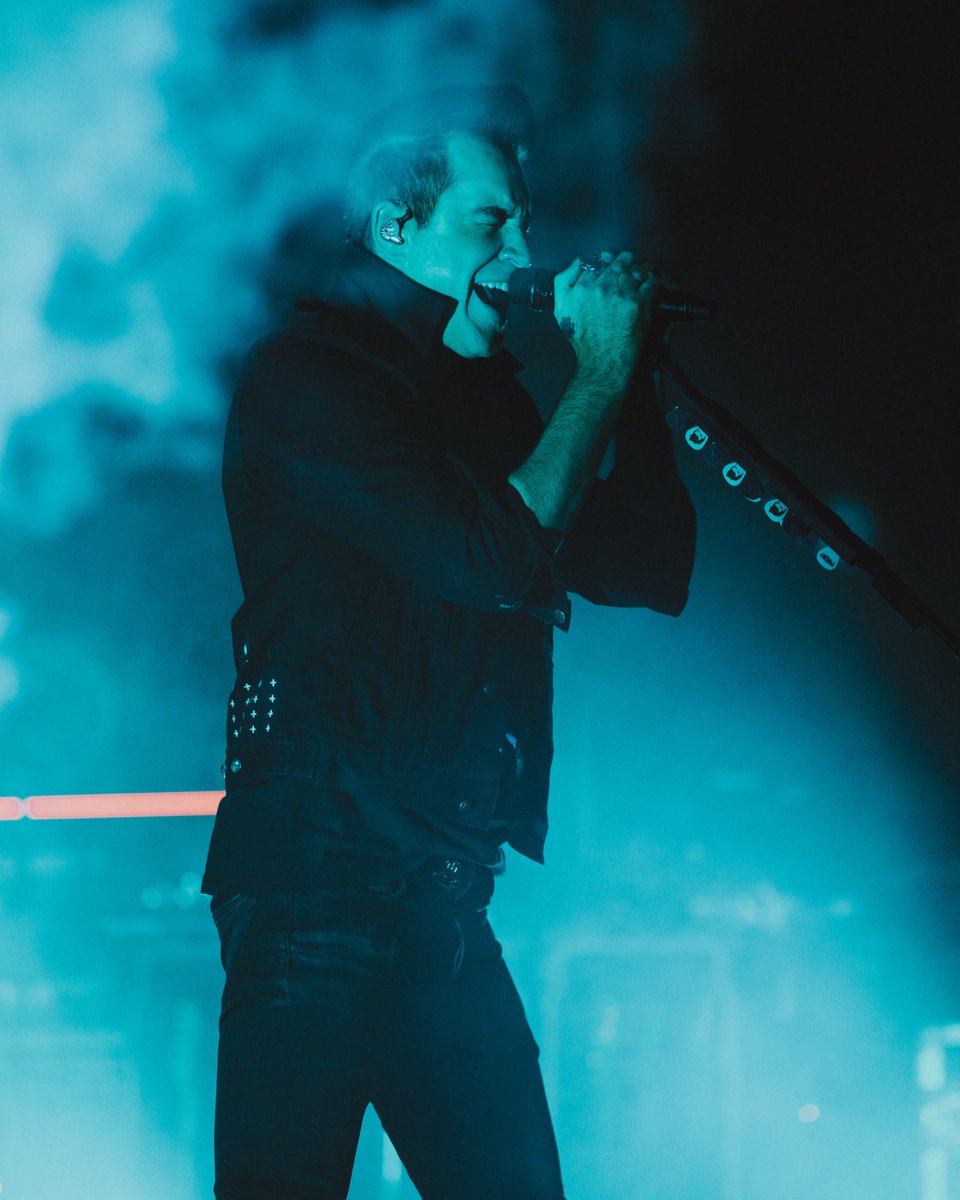 Singer performing intensely on stage with blue smoke around.