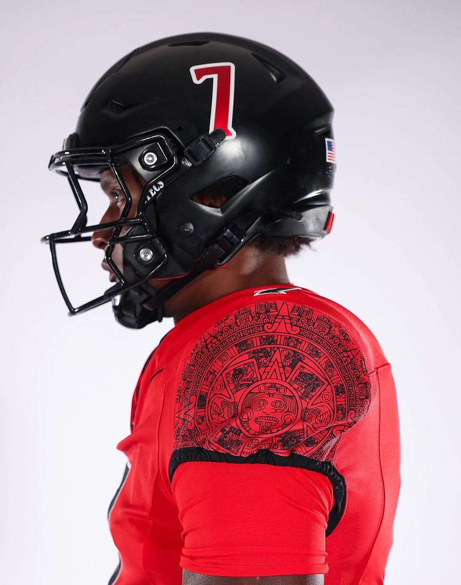 ZachCohenFB's tweet photo. Oh YEAH, job well done by San Diego State!🔥 

Pics & descriptions of their new “Age of the Jaguar” design, per their website:

“The uniform brings together SDSU’s signature red and black palette with a deeper story of strength, courage and identity. The look is anchored by a black helmet, featuring the Ocelotl glyph on one side and the player number on the other.

The Ocelotl mark connects the design to the jaguar’s historic symbolism: power, valor, and military prowess, and linked to health, grit, and perseverance. In Aztec tradition, Ocelotl represents Tezcatlipoca, god of the night sky, memory, and time. The jaguar also represents elite warriors who embodied discipline, bravery, and strength in battle.

“The Age of the Jaguar” extends the Glyphs iconography introduced last year, bringing that visual language from brand storytelling into the on-field uniform system. The Ocelotl glyph is the centerpiece of the helmet, while the custom sublimated artwork on the jersey sleeves and pant side panels carries the same sense of cultural texture throughout the full look.

Together, the uniform is designed to be bold from a distance and meaningful up close. It honors cultural symbolism, reflects San Diego State’s visual identity, and creates a modern on-field expression of confidence, strength, and competitive edge.”