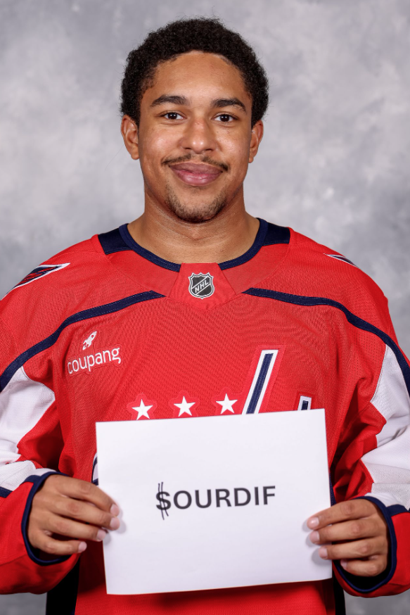 Justin Sourdif holds up a piece of paper with his last name reading "$OURDIF" before taking his headshot at Media Day.