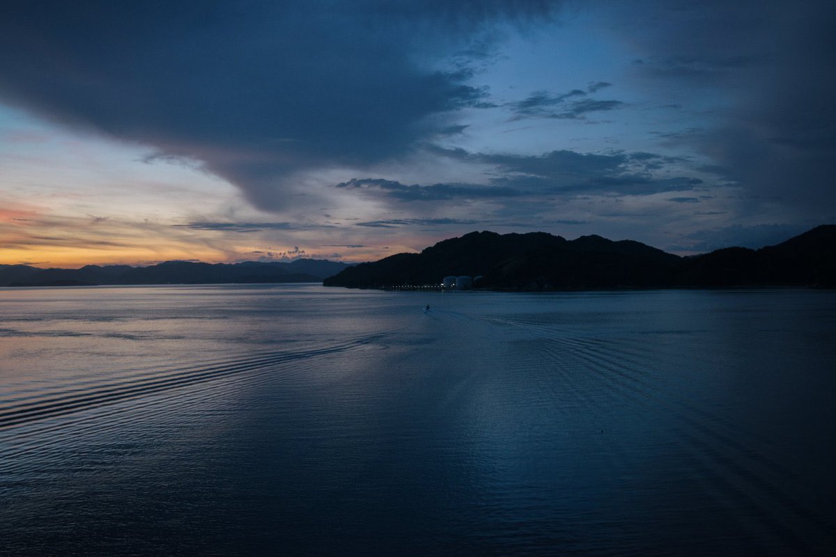North_ern2's tweet photo. 私も初めて瀬戸内海に行ったときの衝撃が今も頭に焼き付いてる。海との距離が近いんだ。これは単に物理的な距離じゃあなくて精神的な距離の話。瀬戸内海から九州あたりの海は、海が生活空間そのものになってきて陸と分離してない。日常の領域、道の一つになってる。島がそこらじゅうにあって対岸との距離も近く、渡し船もたくさんある。「海も生活の場」という感覚が自然に発生する。一方で北の海は「海がそこにある。でもそこは自分の足がつかない『目に見える異空間』」という感覚になる。北海道の海の「人の手出しが効かない世界」「冷たい怒濤、蒼と黒の人外領域」「この向こうには何もない、人を拒絶する海。そこへ駆り出る漁師さんや船乗りが勇者に見える世界」とはまるで違うように瀬戸内の穏やかで島がそこらじゅうにある海は目に映る。私は出身が函館で、生まれて20余年365日フェリーや漁船、青森の対岸を見て生きてきたが、それでもそんな意識なのだ。気候や風景、環境が人の心に与える影響は想像するよりかなり大きいと私は思っている。