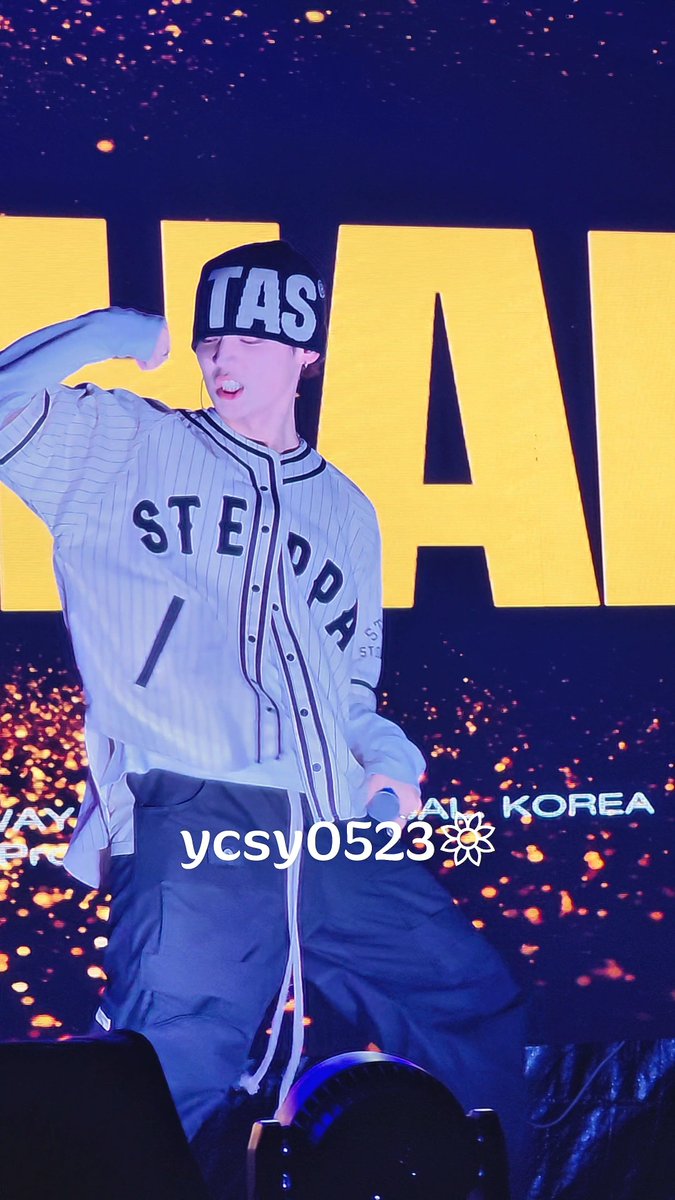 A performer in a white pinstriped 'STEDA' jersey and beanie dances energetically on stage with 'KOREA' visible on the backdrop, watermarked 'ycsy0523'.