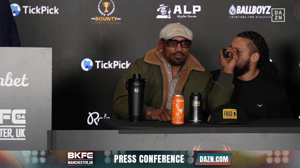 Yoel Romero and Darren Till sit side-by-side at a BKFC press conference, with Till appearing to wipe his eye while Romero looks on, as promotional banners for BKFC94 Manchester, TickPick, ALP, Ballboyz, and a "Press Conference" graphic frame the scene ahead of their September 26 matchup streaming on DAZN.