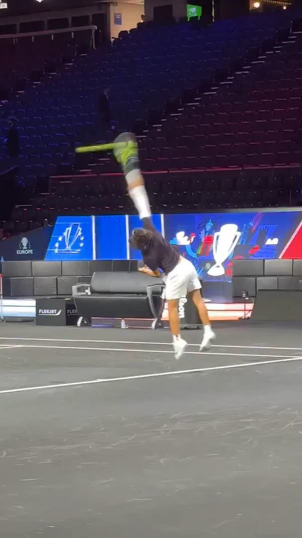 A tennis player, identified as Carlos Alcaraz, is captured mid-air in an acrobatic pose on a court, appearing to perform an athletic flip or handstand. In the background, "EUROPE" and "LAVER CUP" signage is visible along the stadium barrier, confirming the event setting mentioned in the post.
