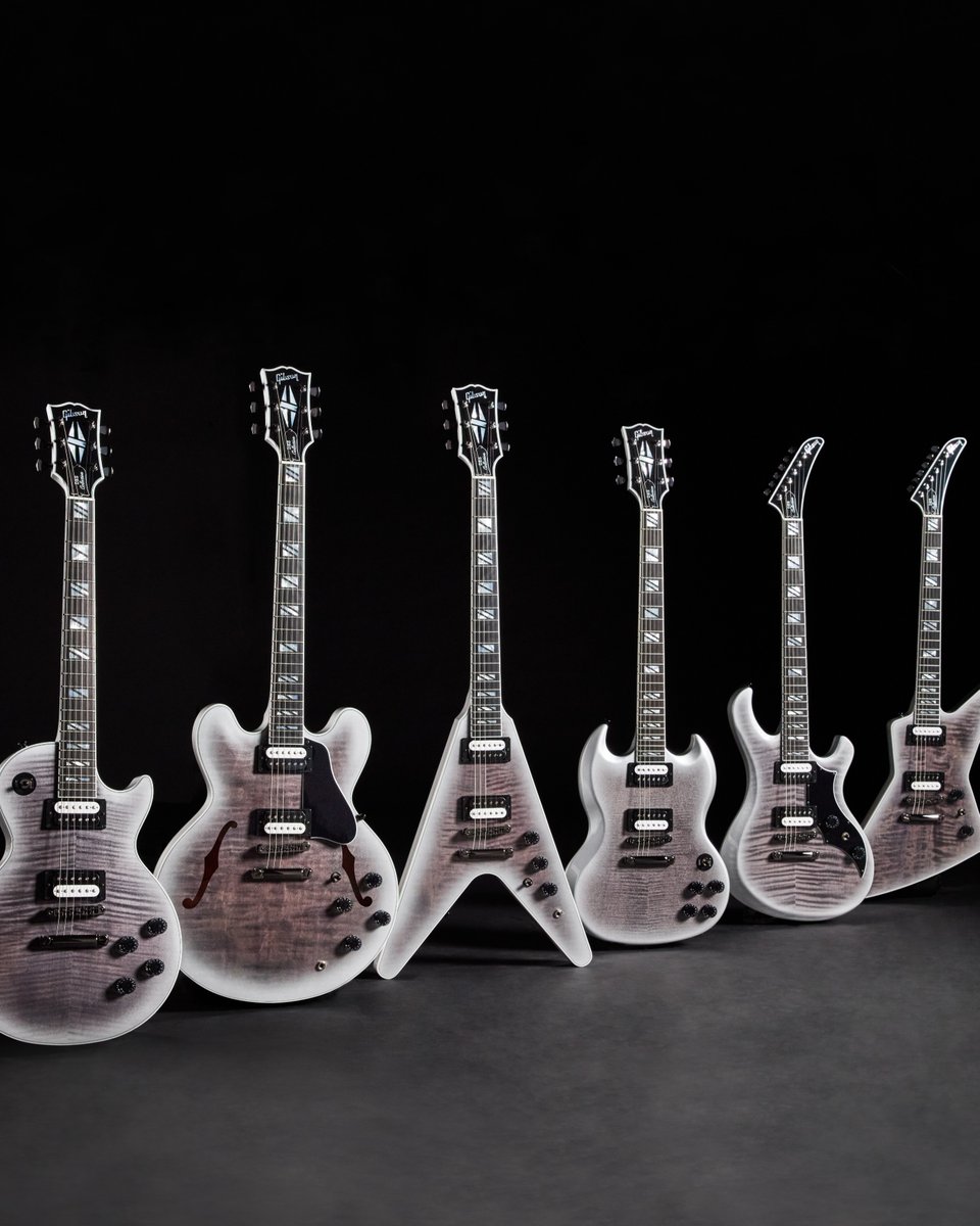 A row of guitars from the Gibson DES Collection electric guitars is displayed against a black background. Each guitar has a glossy finish and unique body shape, showcasing intricate design details and polished hardware.