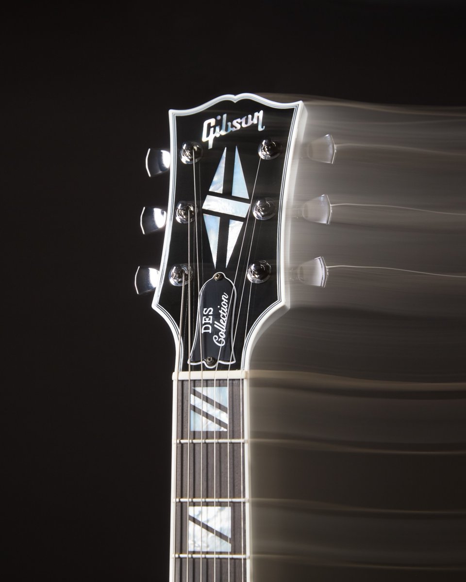 Gibson guitar headstock with motion blur effect on the tuning pegs. Truss rod cover says DES Collection.