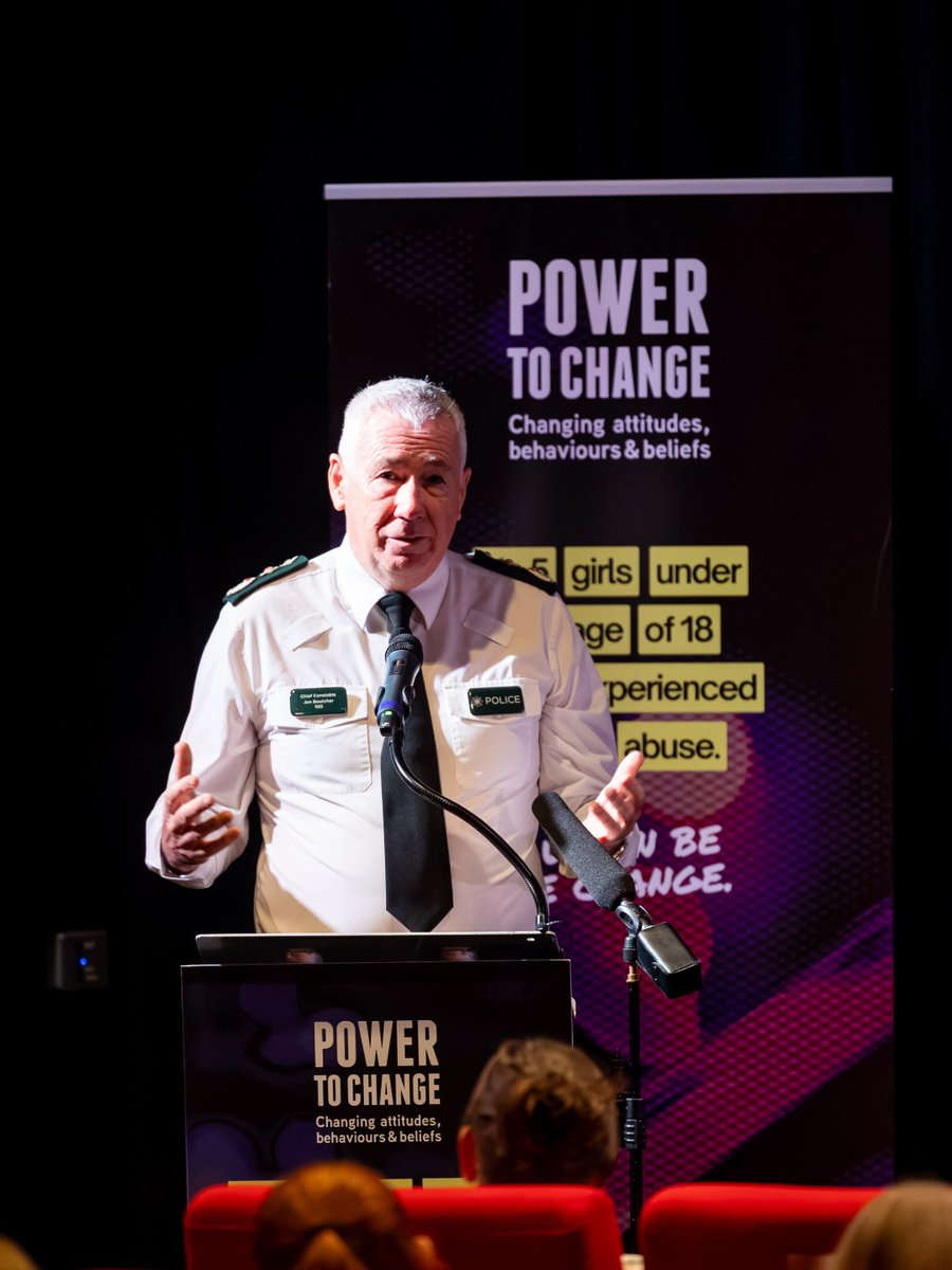 PSNI Chief Constable Jon Boutcher speaking at a podium in front of a 'Power to Change' campaign banner.