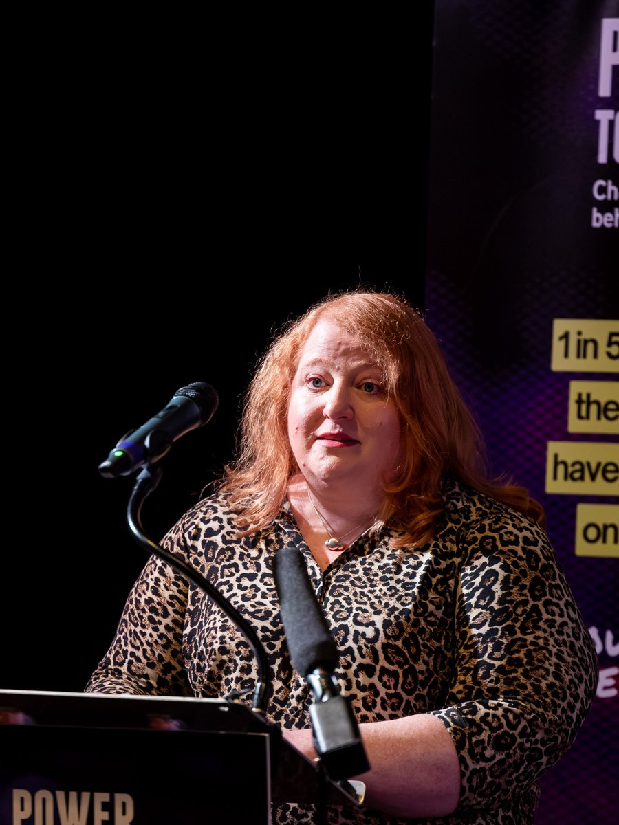 NI Justice Minister Naomi Long speaking at a podium in front of a 'Power to Change' campaign banner.