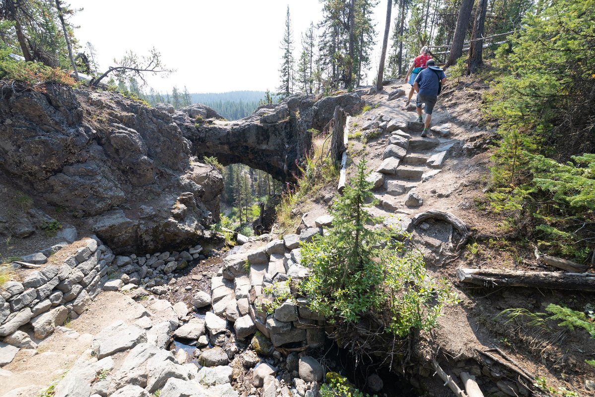 Hikers on a trail near a natural rock archway