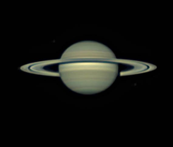 Large planet with goldish-tan banded clouds and huge rings around it.