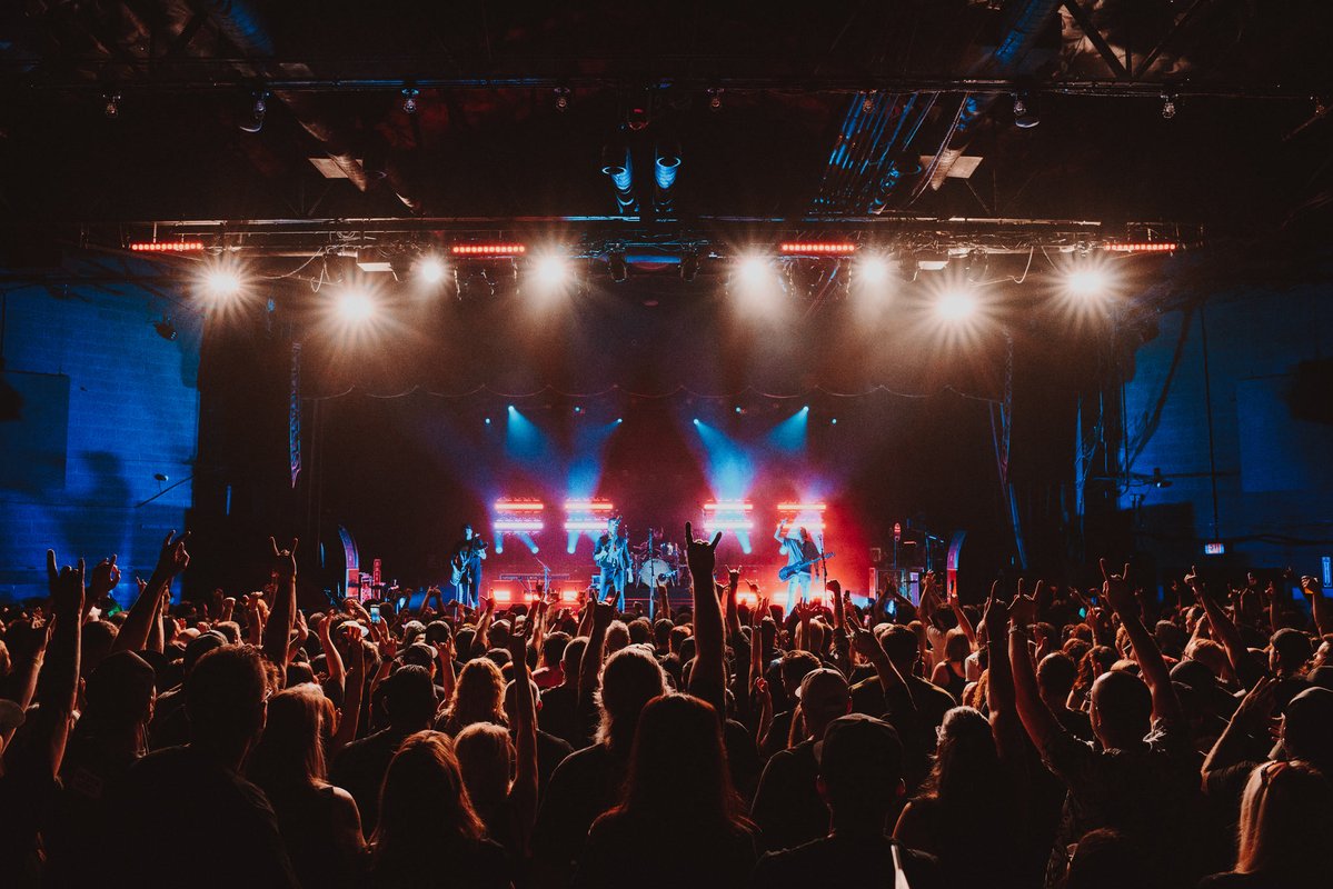 Concert crowd in a venue with bright stage lights.