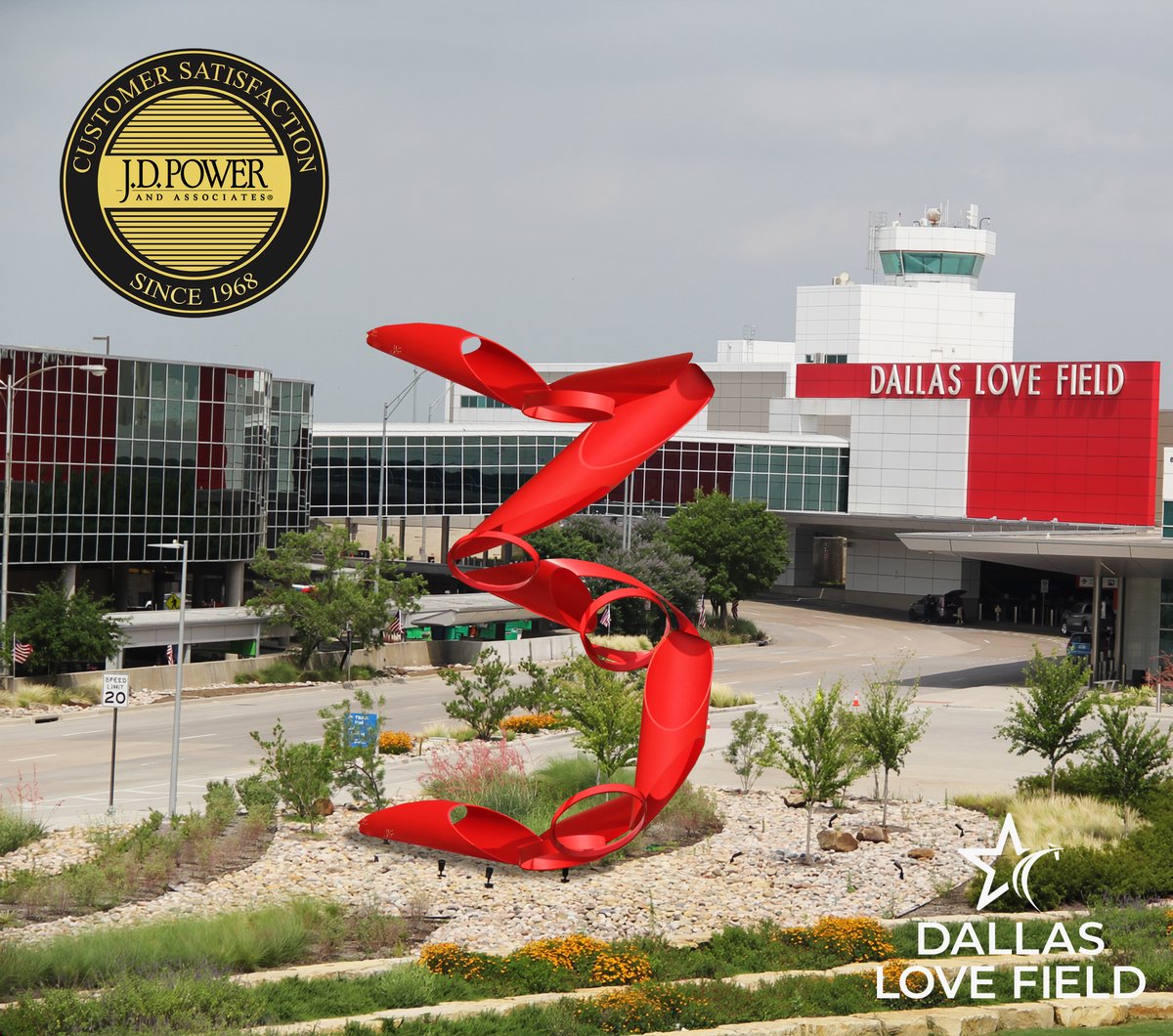 The image shows the exterior of Dallas Love Field Airport with J.D. Power Customer Satisfaction emblem. A large red abstract sculpture, forming the number three, is in the foreground, surrounded by greenery and flowers. The airport building displays "Dallas Love Field" signage, with the control tower visible above.
