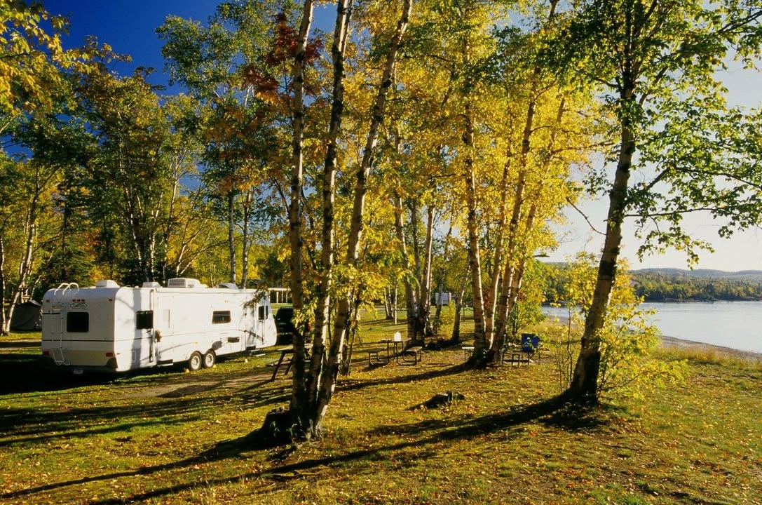 Trailer parked next to lake under trees