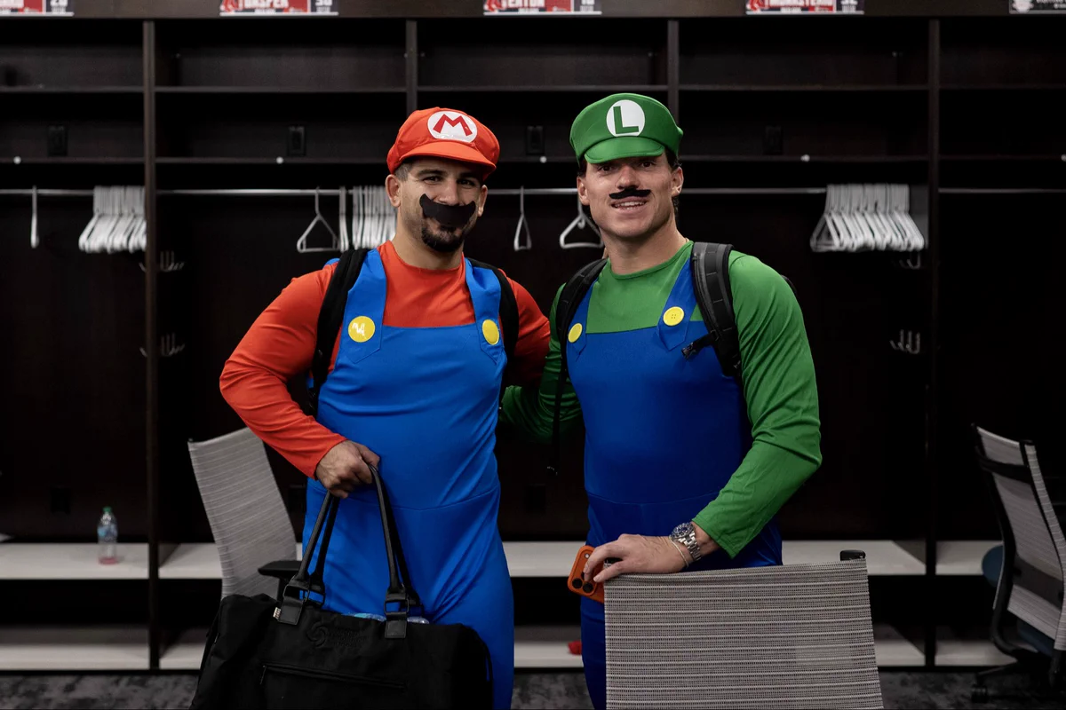 Mickey Gasper and Nate Eaton are dressed as Mario and Luigi posing for a photo in the visiting clubhouse.