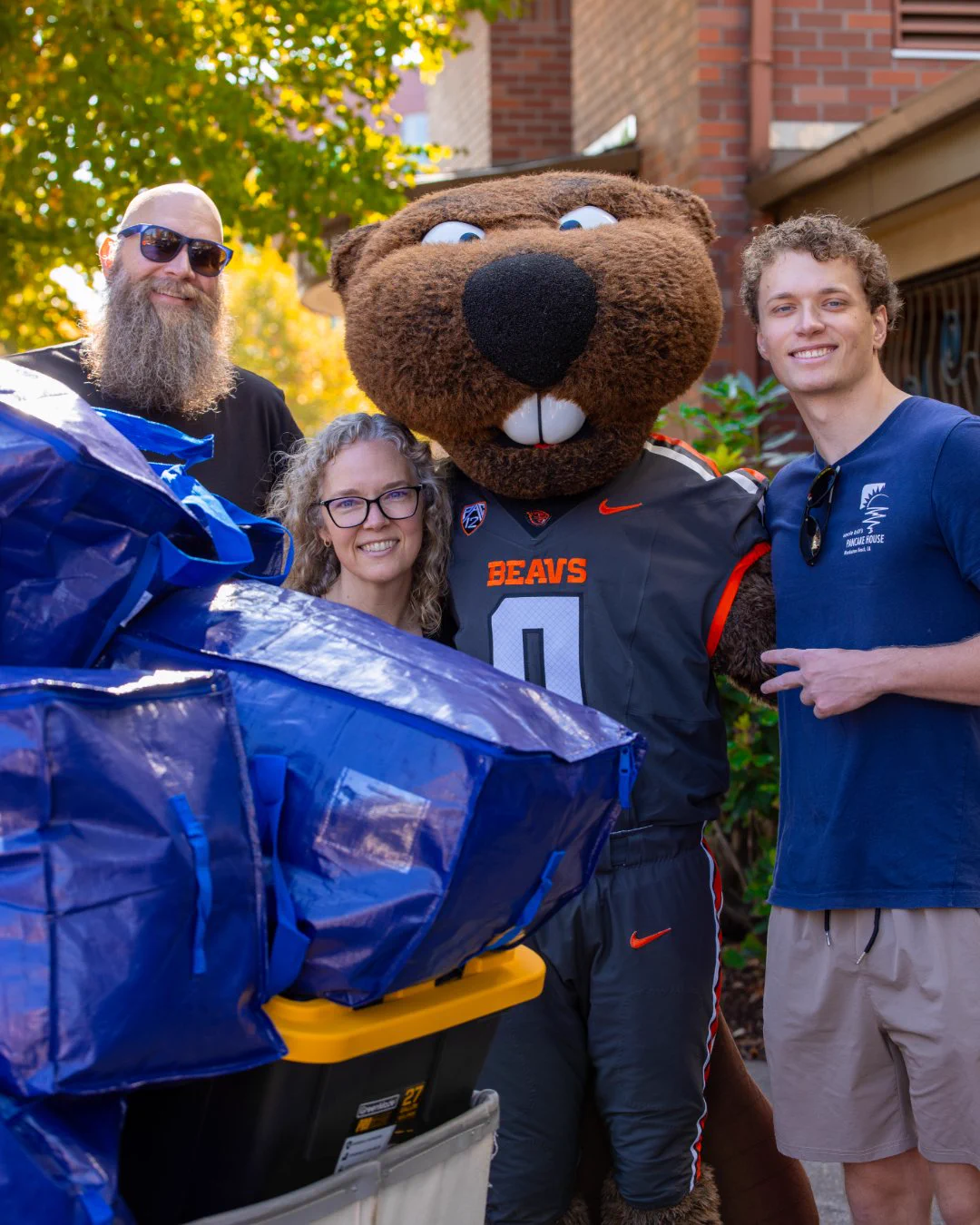 Family smiles with Benny Beaver during Oregon State University move-in week.