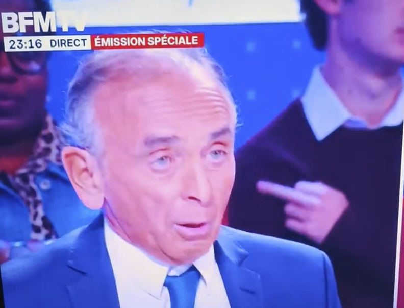 ojim_france's tweet photo. 🔴Lors de la soirée spéciale consacrée à Éric Zemmour, BFMTV a bien placé derrière lui un militant de gauche qui a désapprouvé l'homme politique par un doigt d'honneur et des hochements de tête. Des saisines adressées à l'ARCOM. https://t.co/scZM1DQ68B