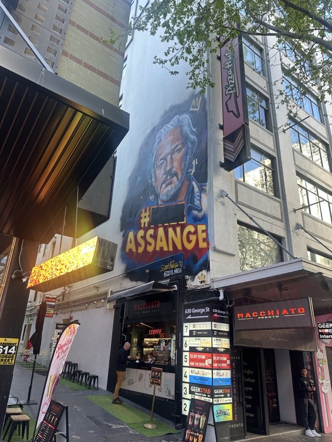KillAuDeepState's tweet photo. I was going to check out the Assange mural on the main street of Sydney (George Street) but @P_Ellison17 saved me the time by taking this photo.

What strikes me is the countdown is revealed as only 7 to 2.

@JulianAssange took his photo on 9/17/26 and thus five days later it corresponds to 9/22 (ie: Twosday)

Also B = 2 and Y = 25 hence ‘Bold Brew Bold You’ = 22225 = 22/9

Anyways, I still reckon the decode actually refers to the incoming EAS test scheduled on 11/17/26 at 2:20pm - because the timestamp of Q529 is one second (human error) from 11/17

But then again Q529 = 22/9 as 5 = 11 (opposite on the clock) = 1 + 1 = 2 so double meanings could exist. 🤪