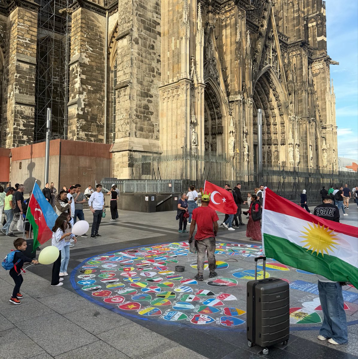 DrTugrulcan's tweet photo. Köln’de bayrak draması 😂

Elemanlar bayrakları yere çizerek kendilerince sokak sanatı yapıyor. Bizimkiler “Türk bayrağı yerde olmaz” deyip bayrağı astırıyor. Yetmiyor, Azerbaycan bayrağını da astırıyorlar. Anlaşılan Kürtler de “Bizim başımız kel mi?” diyip bayrakları üçlemiş :)) https://t.co/Xm3EI0Occ4