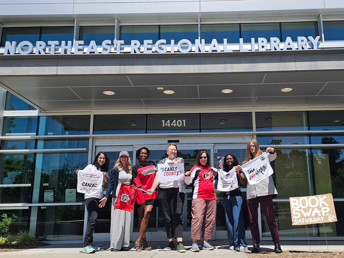 Library staff wearing Canes gear in front of the Northeast Regional Library.