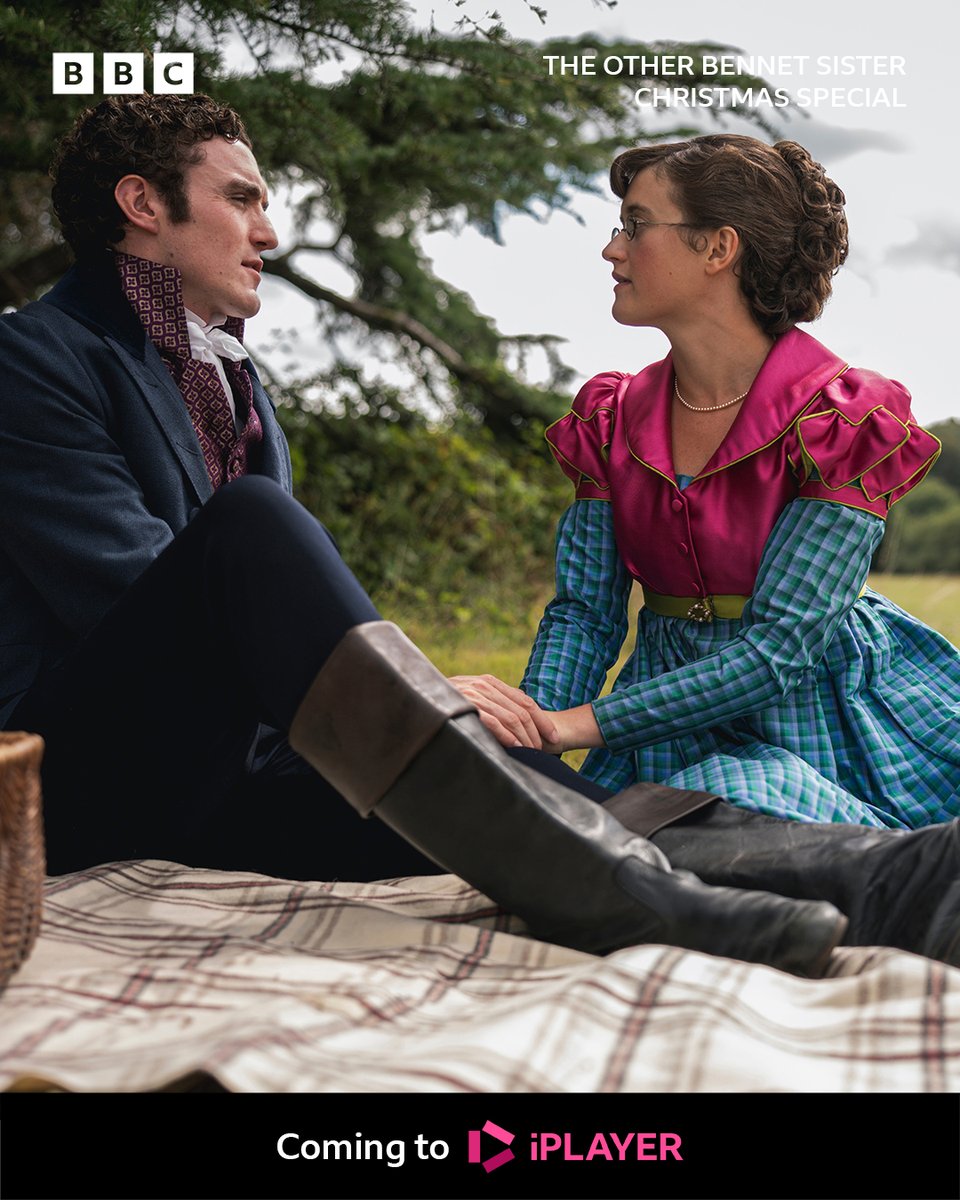 Mary (Ella Bruccoleri) and Tom (Dónal Finn) sit on a picnic blanket in the countryside. Tom holds Mary’s hand as they talk. A wicker basket of food sits beside them. Text on the image reads: The Other Bennet Sister Christmas Special - coming to BBC iPlayer.