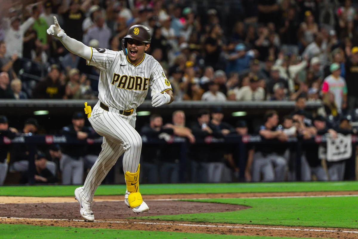 Ethan Salas celebrating. He is wearing the Padres home white pinstripe uniform.