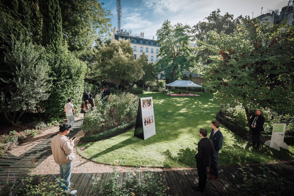 Journées européennes du patrimoine à l'hôtel de Beauvau (ministère de l'Intérieur, Paris) : des visiteurs dans le jardin, autour d'un panneau consacré à l'orchestre de la Police nationale.