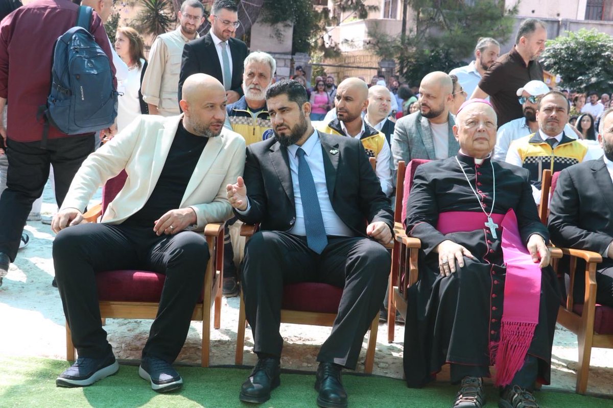 SimNasr's tweet photo. Même endroit 2023 - 2026, 3 ans d’écart. Le prêtre sans soutane est devenu évêque d’Alep, Assad est tombé, le chef des Casques Blancs @RaedAlSaleh3 est devenu ministre, les églises restaurées, les biens restitués et une école catholique fermée par Assad il y a 60 ans rouvre ses portes aux étudiants. Puis je me rappelle tout ce que j’ai pris après ce reportage. Je pourrai dire le temps m’a donné raison, mais ce sont plutôt les Syriens qui m’ont donné raison