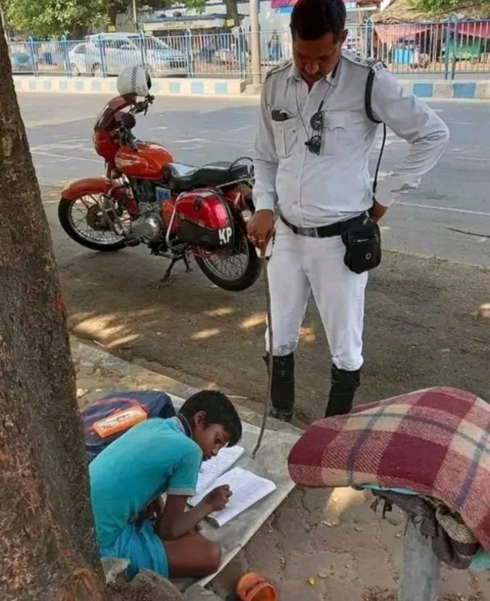 BanCheneProduct's tweet photo. He is traffic police officer Prakash Ghosh, seen here teaching a child by the roadside. Kolkata Police shared this photo with the following caption:

Whenever Officer Ghosh was on duty near the Ballygunge ITI, he would often see a young boy, around eight years old, playing on the street. The boy's mother works at a roadside eatery and toils day and night for her son's better future. Neither mother nor son has a home; they live on the pavement, yet the mother hopes that through education, her son will one day change their circumstances. Upon learning this, Prakash Ghosh felt compelled to act and decided to help them in whatever way he could.

Since then, whenever Officer Ghosh is assigned duty at that location, he teaches the child while simultaneously managing the traffic. Often, he continues to teach the boy even after his shift has ended. Taking on the role of a teacher, Ghosh assigns homework and checks it later. The boy's mother says that there has been significant improvement in her son since he found this new 'teacher'.

Salutes to this traffic police officer. 🫡