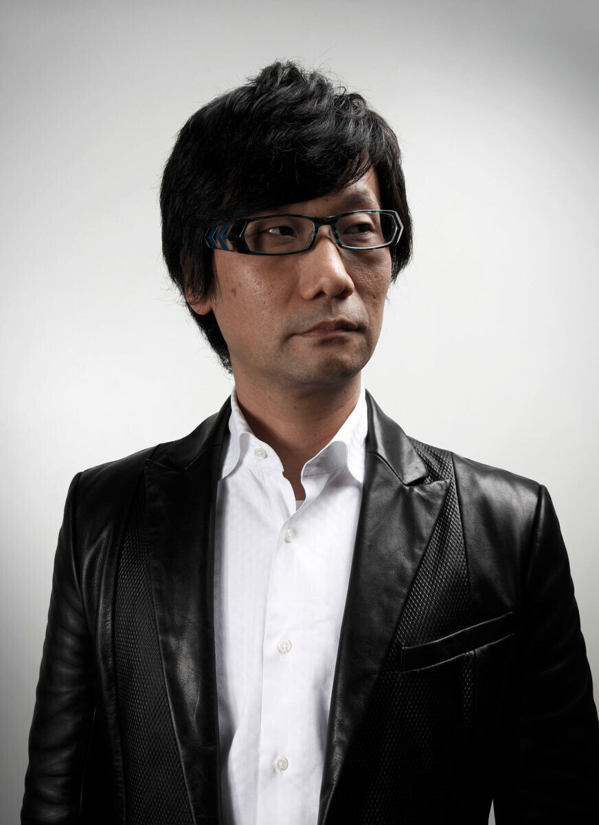 Portrait of Hideo Kojima wearing glasses and a black leather jacket.