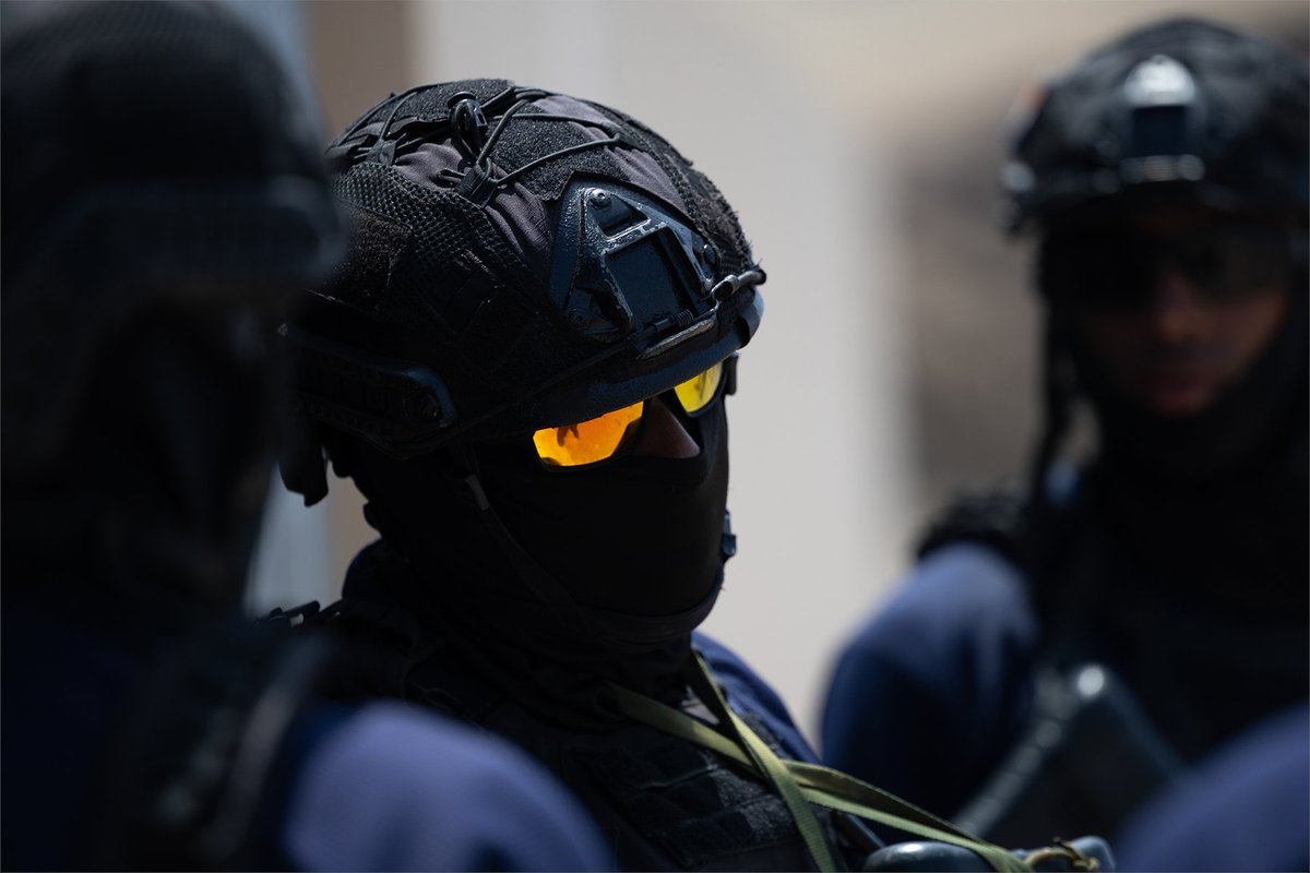 A service member wearing protective gear and amber eyewear prepares for close-quarters training.