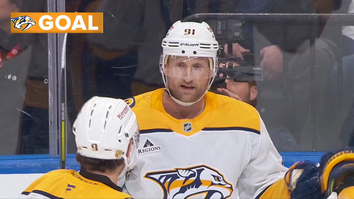 Steven Stamkos (#91) of the Nashville Predators, wearing his white away jersey with "Regions" sponsor patch, stands at the bench during a goal, with the "GOAL" graphic and Predators logo displayed in the top-left corner. The image celebrates his milestone goal that moved him into sole possession of 17th place on the NHL's all-time goals list.