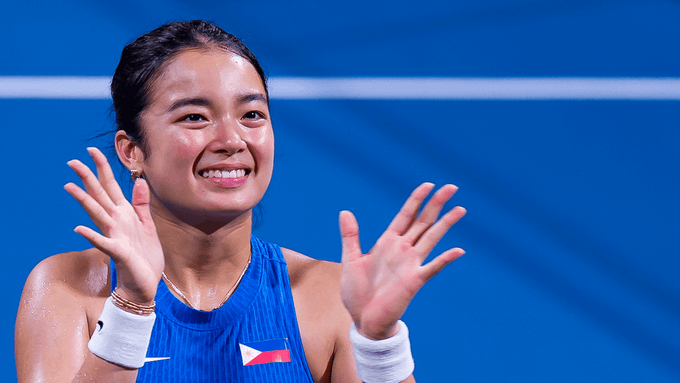 Alex Eala, the Filipino tennis player, smiles brightly and raises both hands in celebration while wearing a blue athletic top with the Philippine flag emblem, capturing a moment of joy likely after a match victory.

The image reflects the post's context of updated WTA rankings, suggesting Eala's rising success that earned her a well-deserved break from the tour.