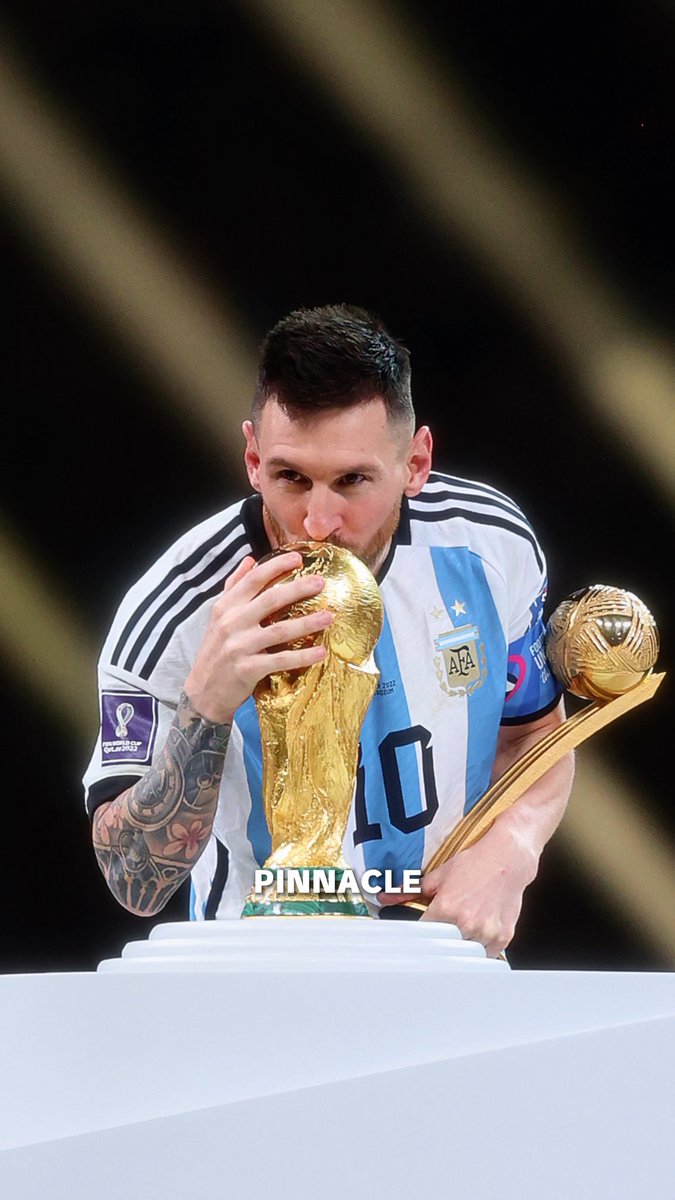 Lionel Messi, wearing Argentina's #10 jersey, kisses the FIFA World Cup trophy while also holding the Golden Ball award following Argentina's 2022 World Cup victory, aligning with the post's tribute to him as the best of his era by Laureus Academy Member Ruud Gullit.