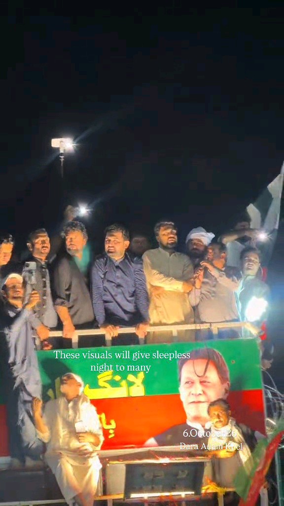 A nighttime political gathering with several men standing on an elevated platform above a green and red banner featuring a portrait, captioned 'These visuals will give sleepless night to many, 6 October 20, Para Adam Khel.'