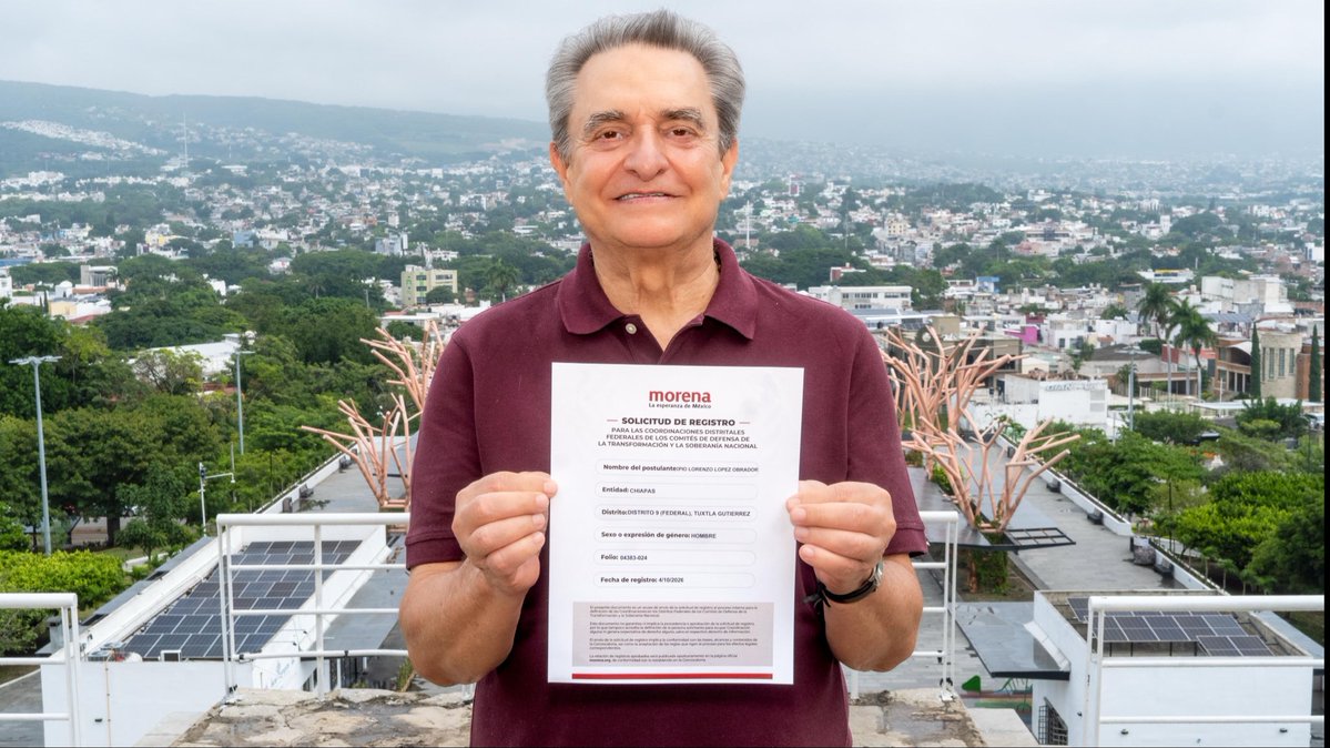 A man in a maroon polo shirt holds up a MORENA party registration document ('SOLICITUD DE REGISTRO') on a balcony with a panoramic view of a city landscape behind him.