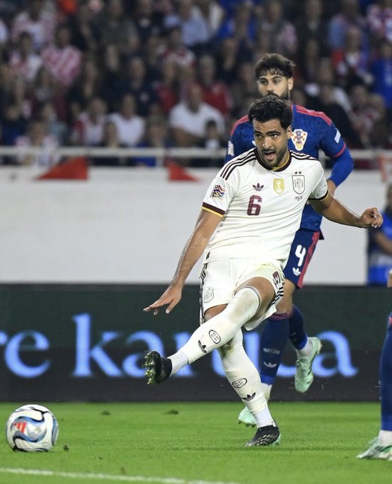 A soccer player wearing the number 6 Venezuela jersey kicks a ball on the field, with a Croatia player (number 4) behind him.