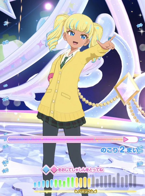 A screenshot from a Japanese rhythm game featuring an anime-style blonde girl in a yellow cardigan and plaid skirt posing on a sparkly stage, with gameplay UI including a rhythm bar and the song title '心当たりリリウム' (Heartfelt Lilium).