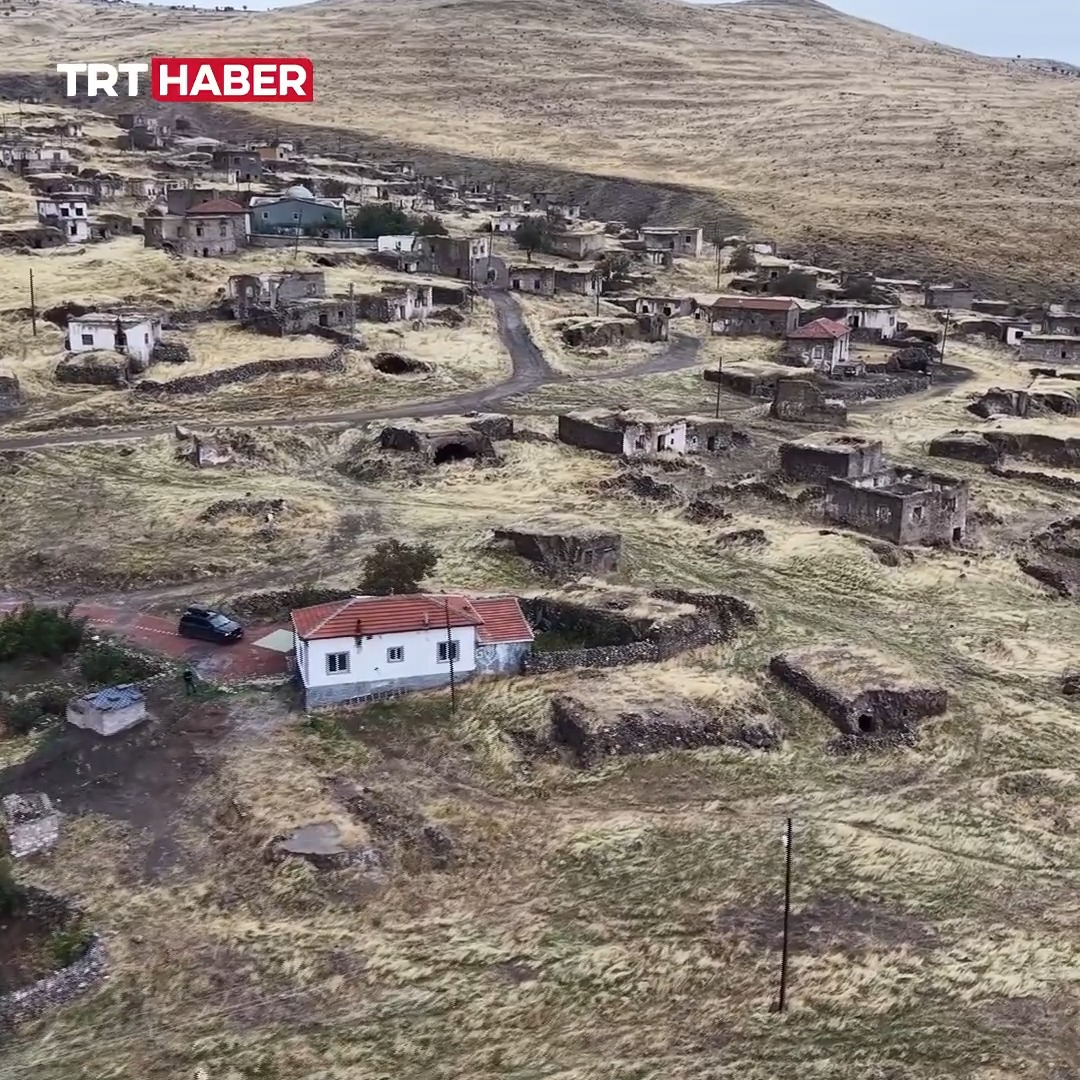 The image, watermarked with "TRT HABER," shows an aerial view of an abandoned village in Aksaray with dilapidated stone houses scattered across a barren hillside, where only one white house with a red roof appears occupied and well-maintained—matching the caption about a 72-year-old man who has lived alone in this village for 11 years after it was abandoned due to water shortage.
