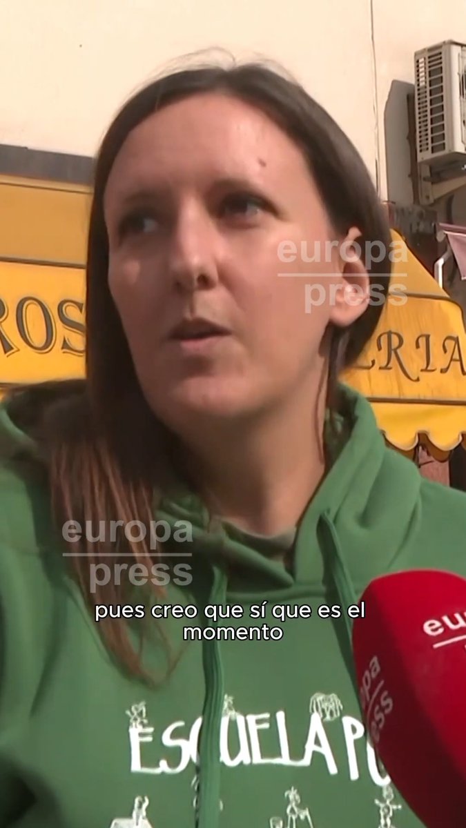 A woman wearing a green "ESCUELA PO..." hoodie is interviewed by Europa Press, with the subtitle reading "pues creo que sí que es el momento," reflecting a citizen's view that it is time for Spanish Prime Minister Sánchez to call general elections, as discussed in the accompanying post.