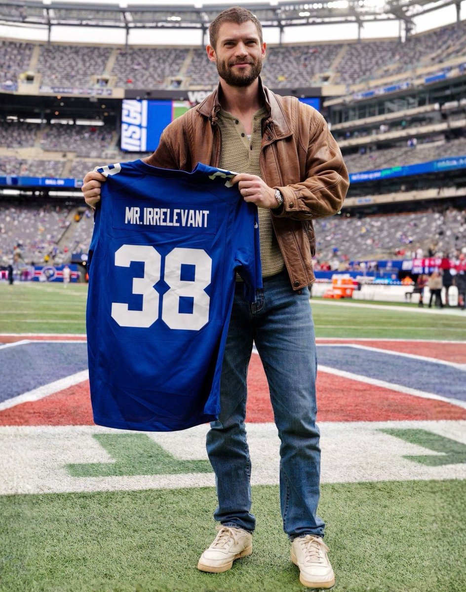 popbuzzz_'s tweet photo. David Corenswet on the field at a New York Giants game, holding up a blue Giants jersey labeled “MR. IRRELEVANT” with number 38, as part of promotional press for his upcoming film.

Corenswet stars as John Tuggle, the 1983 NFL draft’s final selection by the Giants, in the biographical sports drama ‘Mr. Irrelevant’, directed by Jonathan Levine and co-starring Michael Shannon as coach Bill Parcells.

The film, scheduled for theatrical release on December 25, 2026 by Paramount, tells Tuggle’s underdog story of making the roster before his tragic death from cancer at age 25, with this event continuing the press tour after the trailer’s September release.
