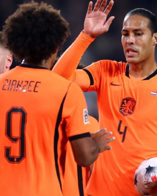 Two soccer players in bright orange Netherlands jerseys high-five; one wears number 9 with 'ZIRKZEE' on the back, the other wears number 4 with the Dutch lion crest.
