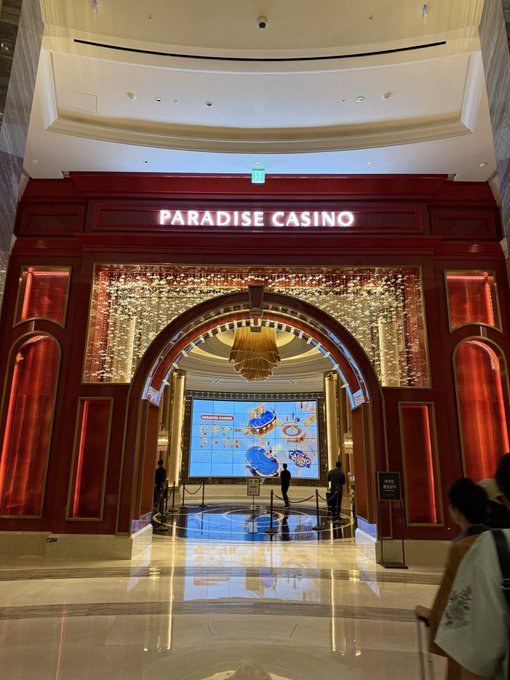 The illuminated entrance of the 'PARADISE CASINO' is shown with a red and gold ornate archway, leading into a brightly lit lobby with chandeliers and digital displays.