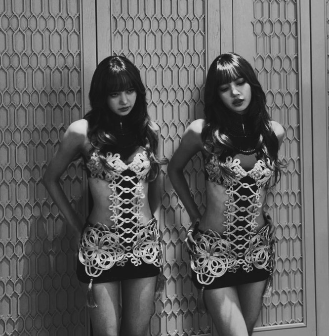 A black-and-white mirror selfie showing a person with long dark hair wearing an intricate lace-up corset dress, duplicated by the reflection.